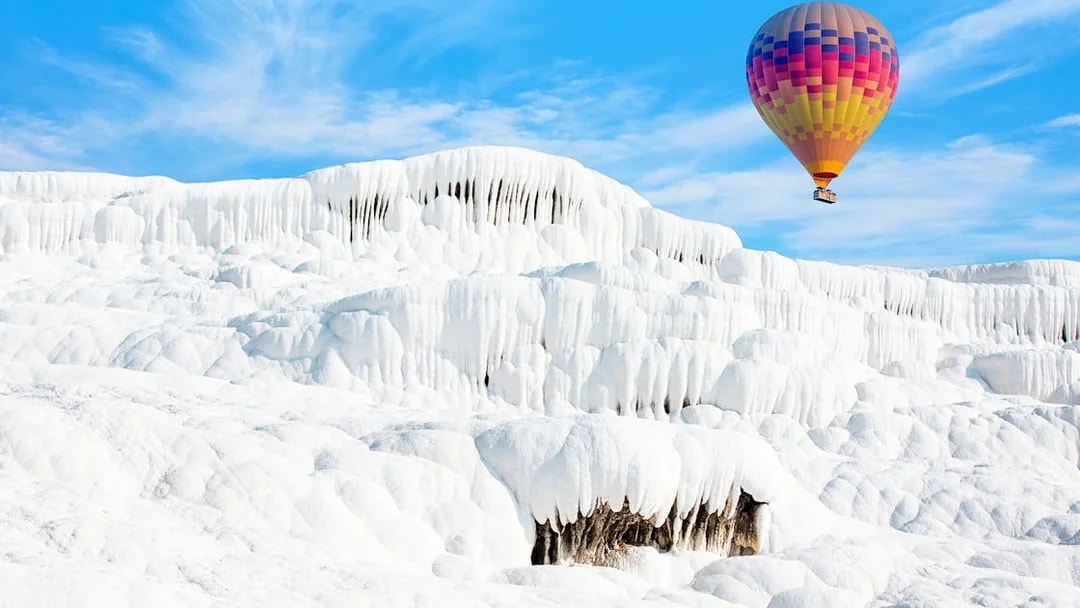 Hot air balloon over travertine terraces in Pamukkale, Turkey.