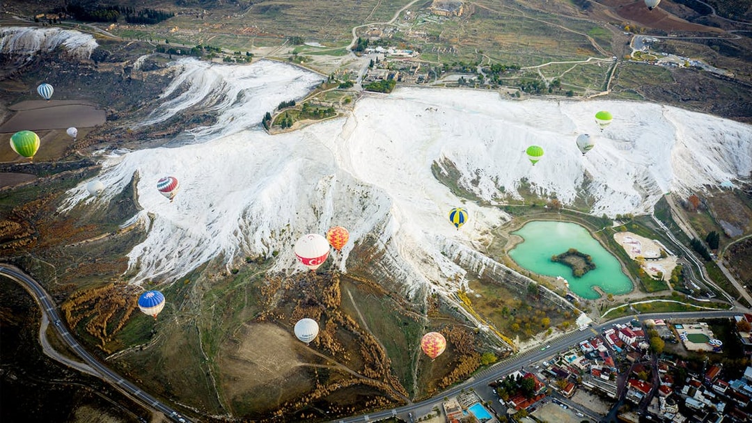 Hot air balloons over Pamukkale's travertine terraces and turquoise pools, Turkey.