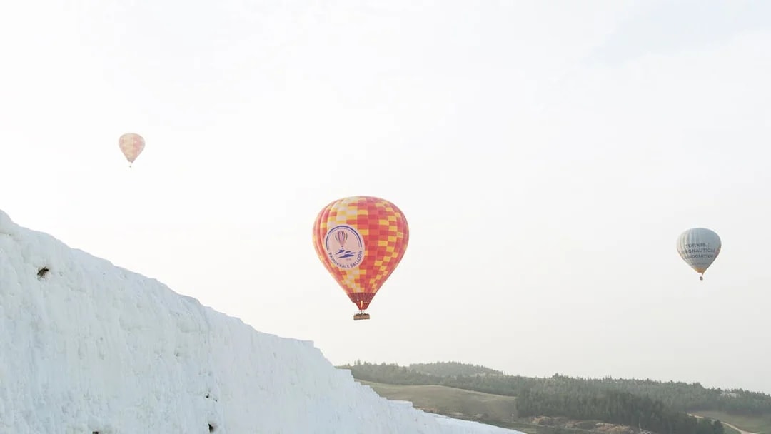 Hot air balloons over travertine terraces in Pamukkale, Turkey.