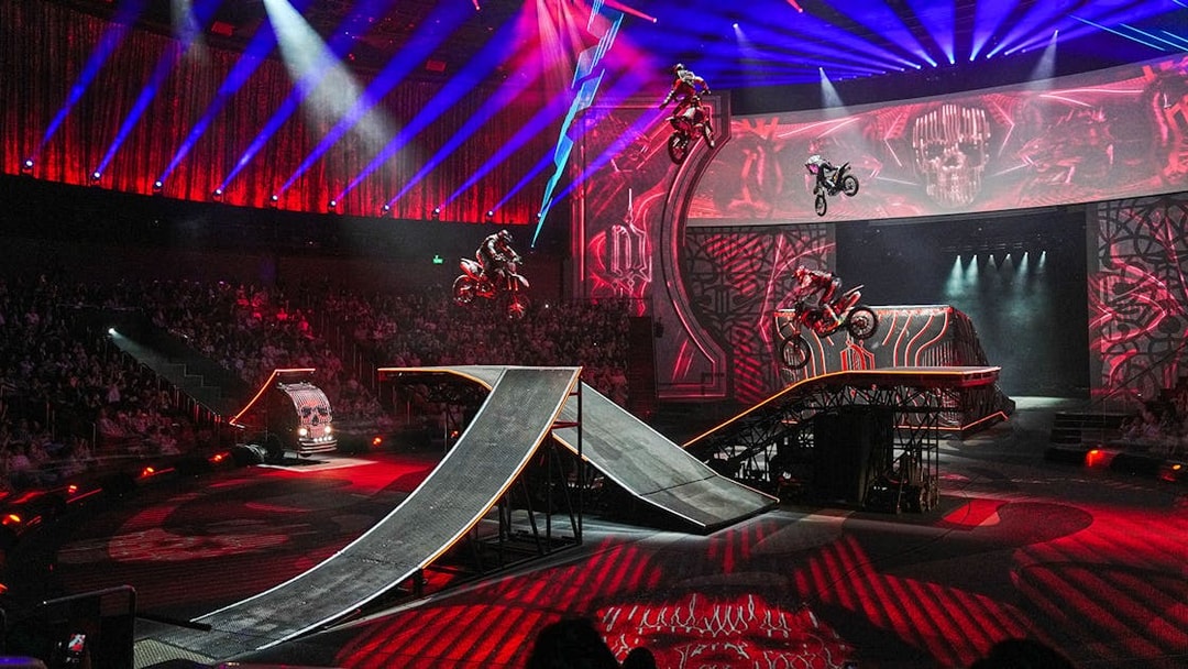 Motorcyclists performing stunts on ramps during House of Dancing Water show.