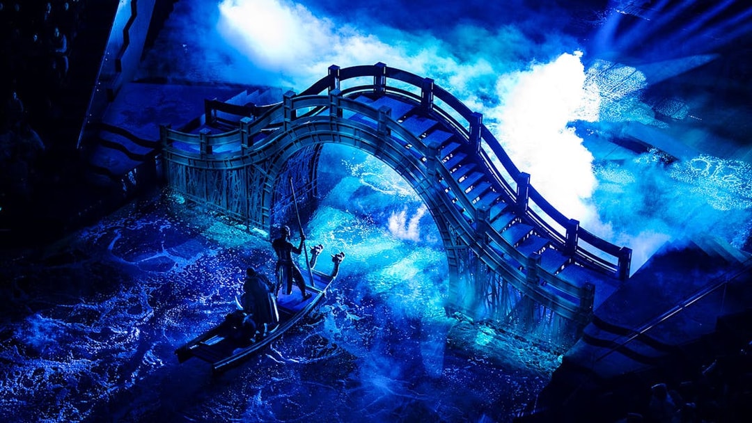 Boat under illuminated bridge during House of Dancing Water performance.