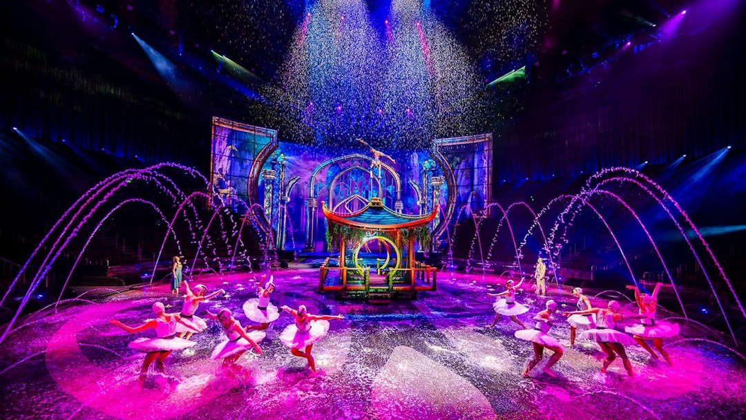 Performers in water dance at House of Dancing Water show, vibrant stage with fountains.