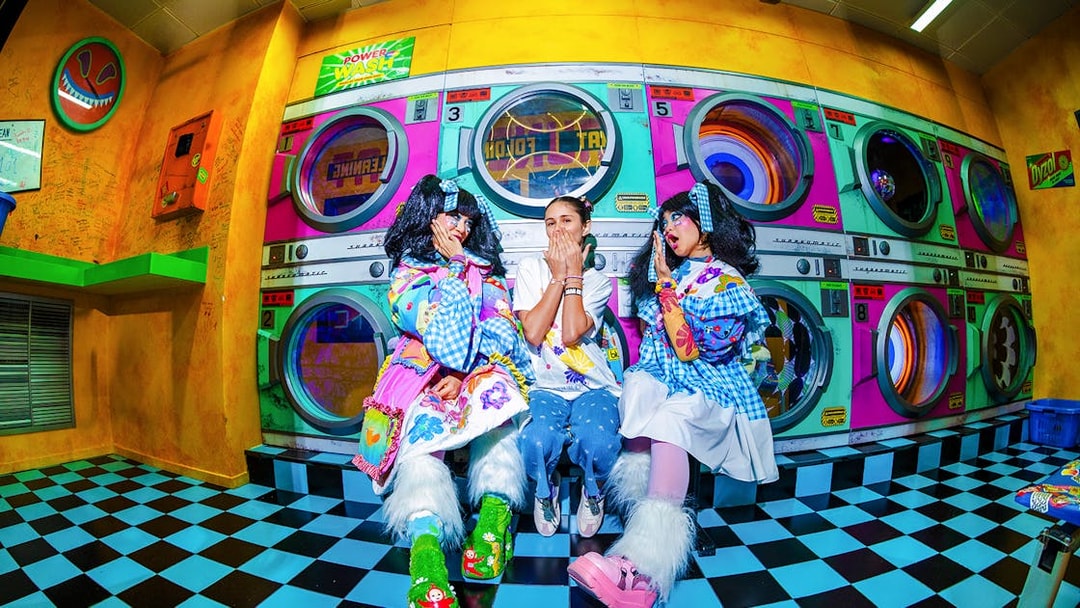 Tourists interacting with performers at House of Hype in colorful laundromat setting.