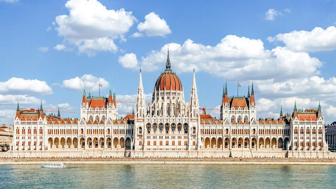 Hungarian Parliament Building in Budapest with Danube River in foreground.