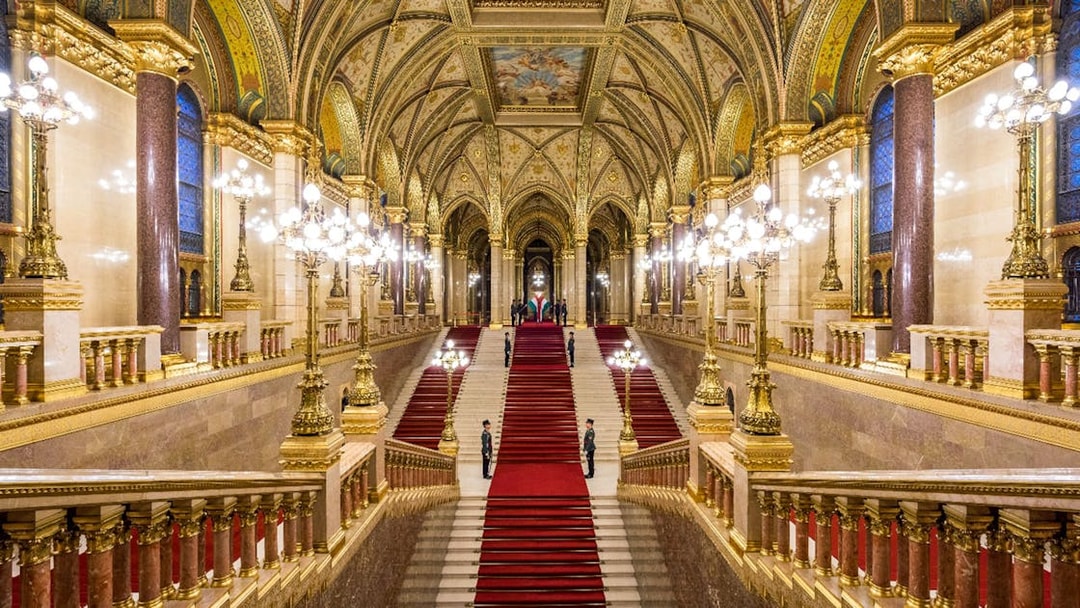 Hungarian Parliament grand staircase with ornate ceiling and red carpet in Budapest.
