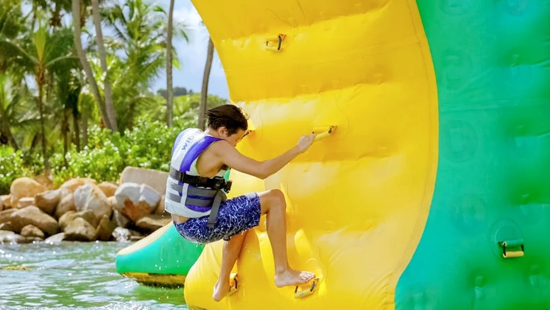 Person climbing inflatable obstacle at HydroDash Singapore water park.
