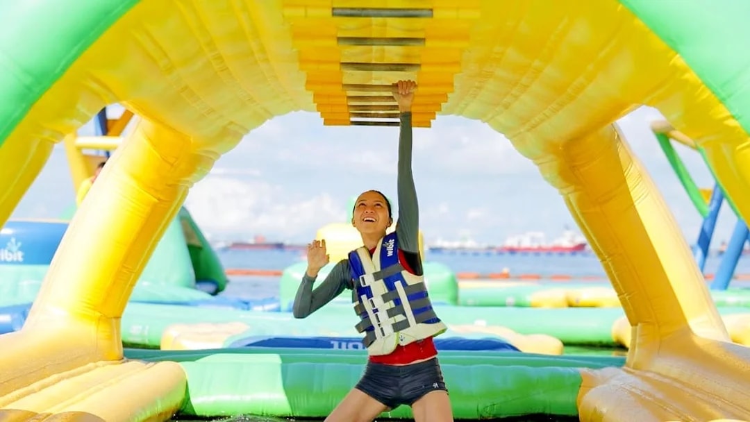 Person climbing inflatable obstacle at HydroDash Singapore water park.