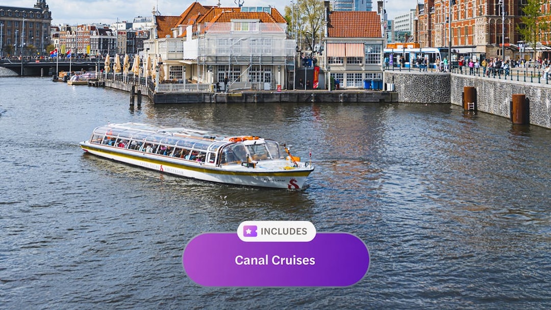 Canal cruise boat on Amsterdam canal with historic buildings in the background.