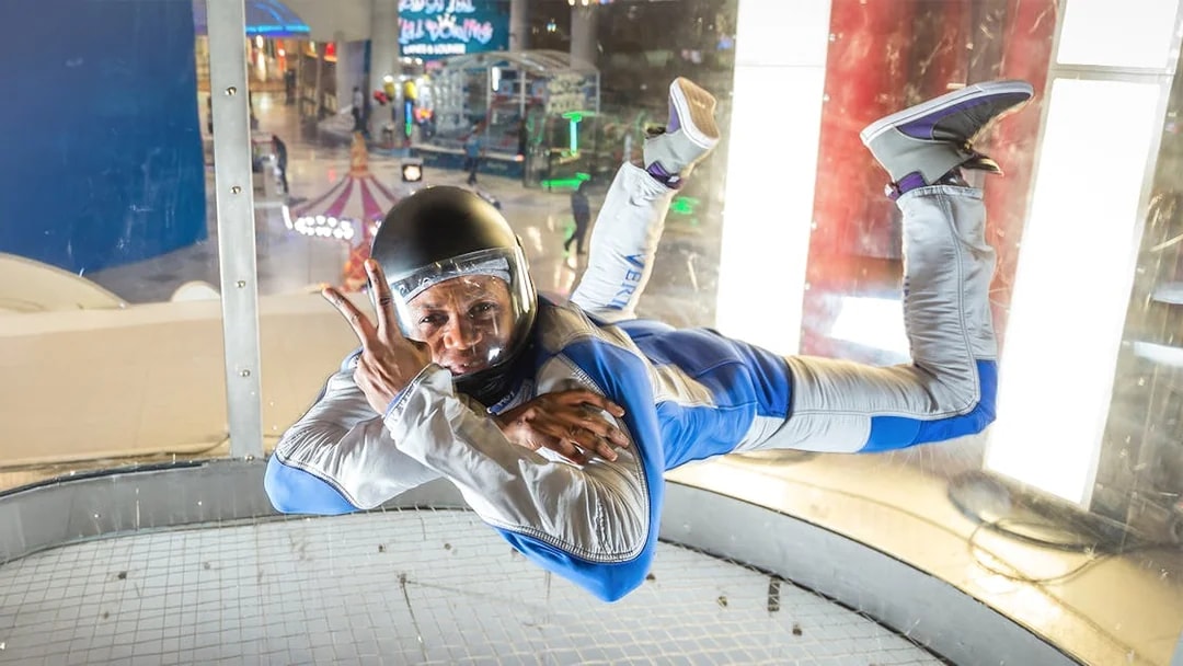Instructor demonstrating iFly Dubai indoor skydive in wind tunnel.