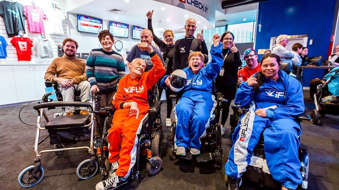 Group of people in wheelchairs celebrating at iFLY Indoor Skydiving Experience.