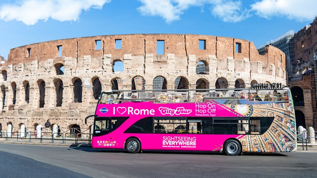 Open-top tour bus in front of the Colosseum, Rome, for I Love Rome Hop-On Hop-Off Tour.
