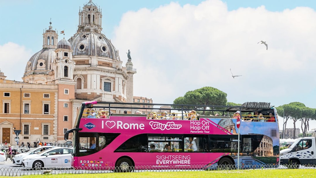 Open-top tour bus in Rome near historical architecture.