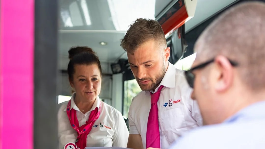 Tour guides assisting a passenger on the I Love Rome Hop-On Hop-Off bus tour.