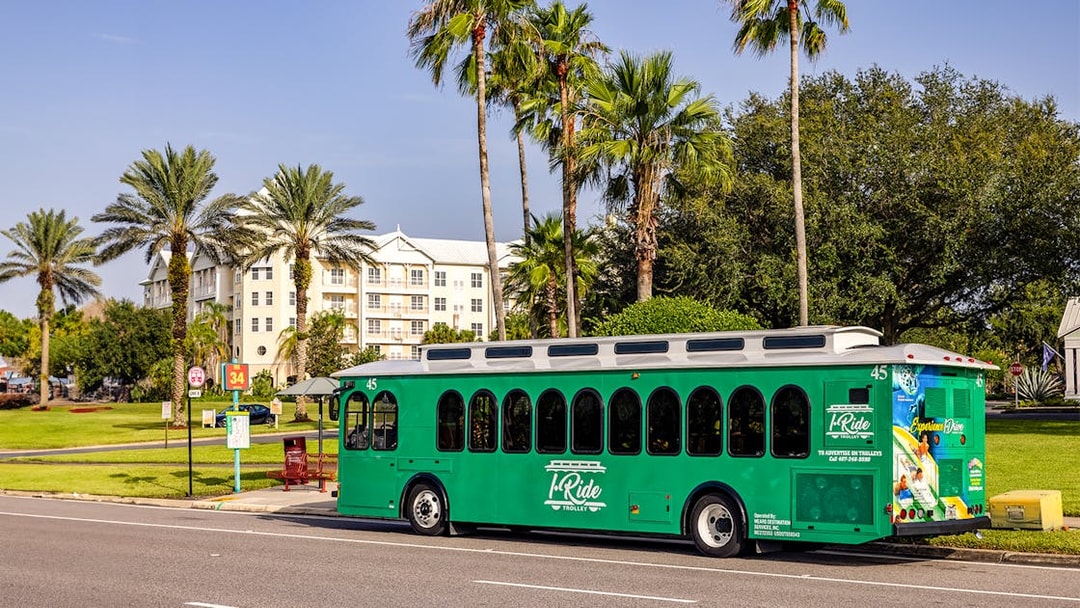 Orlando I-Ride trolley bus parked near palm trees and a residential building.