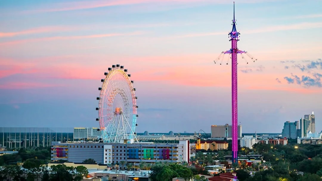 Ferris wheel and swing ride at sunset in Orlando amusement park.