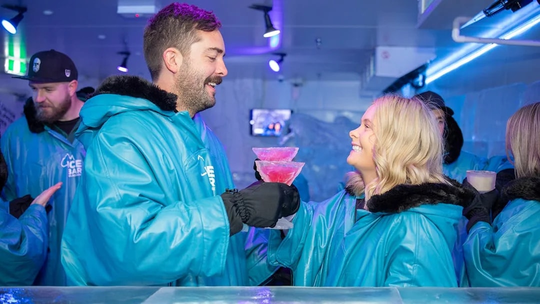 Couple enjoying cocktails at IceBar Surfers Paradise in blue parkas.