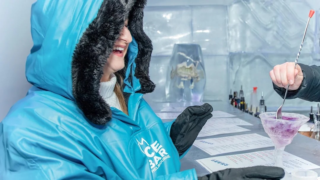 Person enjoying a drink at IceBar Surfers Paradise, wearing a blue parka.