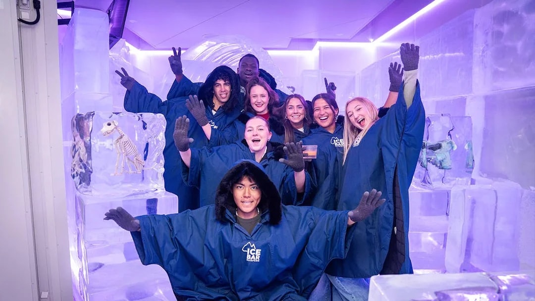 Group enjoying IceBar Surfers Paradise in winter coats, surrounded by ice sculptures.