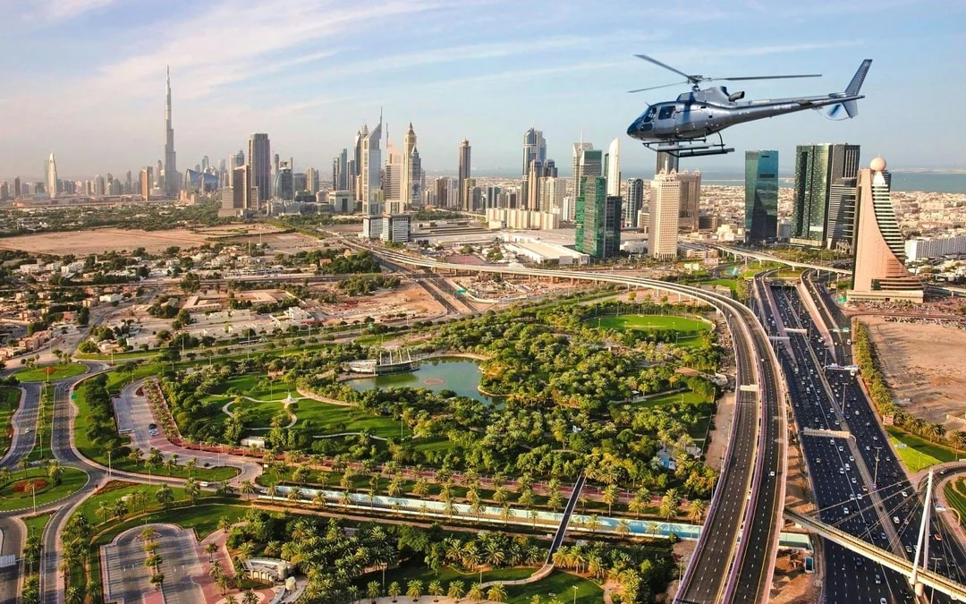 Helicopter flying over Dubai cityscape with Burj Khalifa in view.
