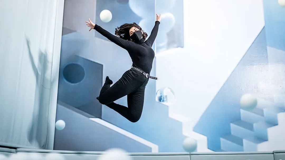 Person jumping in a room with geometric art at Ikono in Madrid.