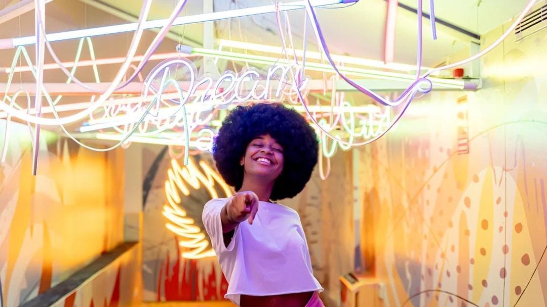 Person smiling under neon lights at Ikono in Madrid.