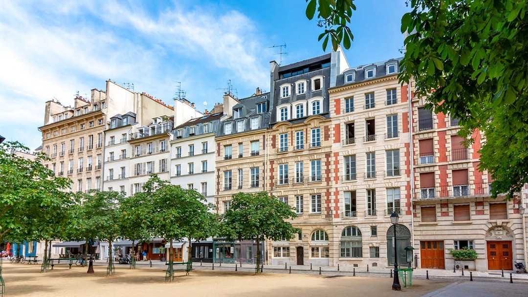 Historic buildings on Notre Dame Island, Paris, with trees lining a quiet square.
