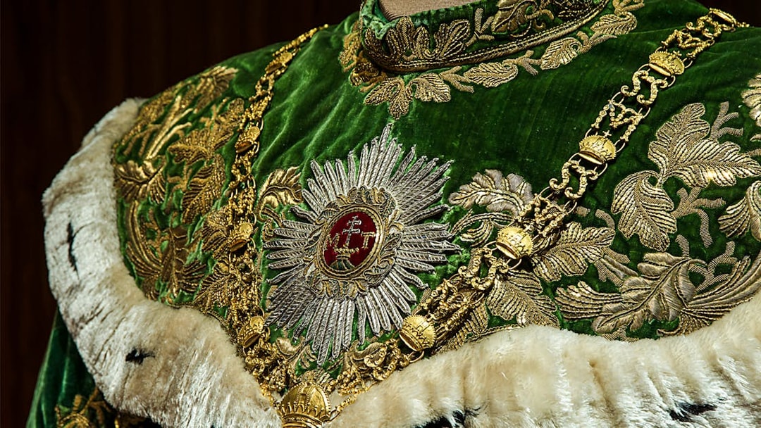 Ornate green and gold robe with intricate embroidery at Imperial Treasury Vienna.