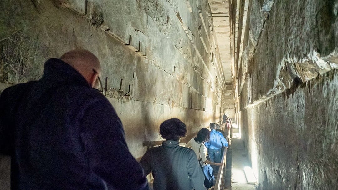 Visitors walking through a narrow passage inside Khufu's Great Pyramid.