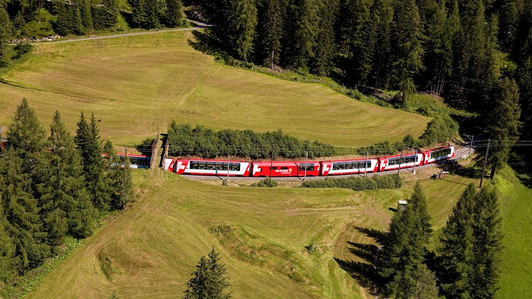 Glacier Express train traveling through lush Swiss countryside with Interrail Pass.