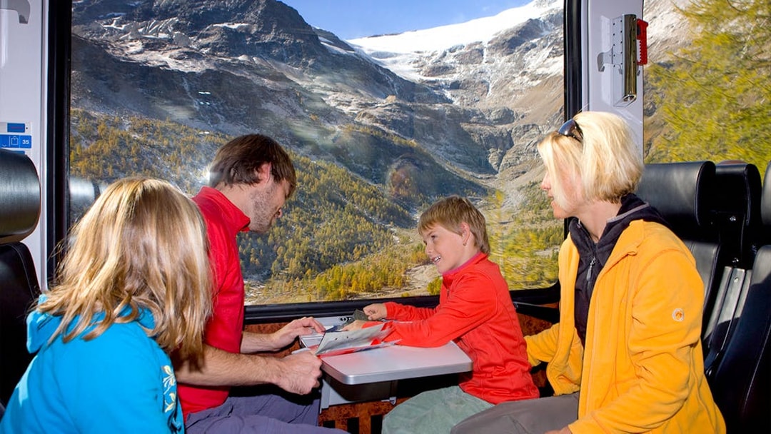 Family enjoying scenic views on the Bernina Express in Switzerland with Interrail pass.
