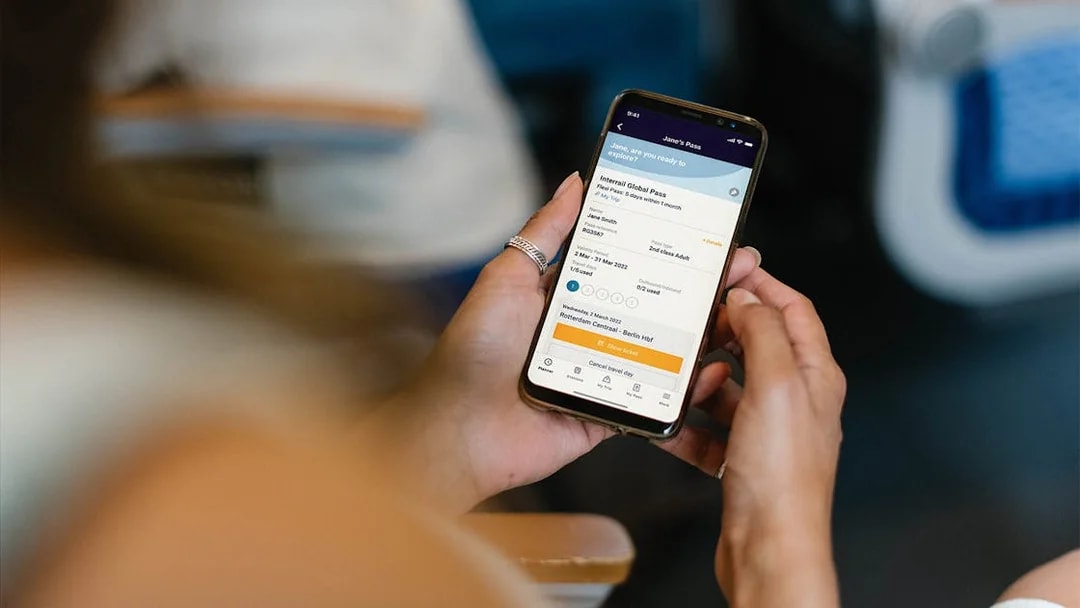 Person holding phone displaying Interrail Global Mobile Pass Flex booking.