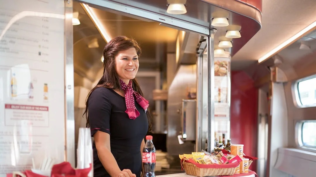 Train attendant serving snacks and drinks on an Interrail Global Mobile Pass Flex journey.