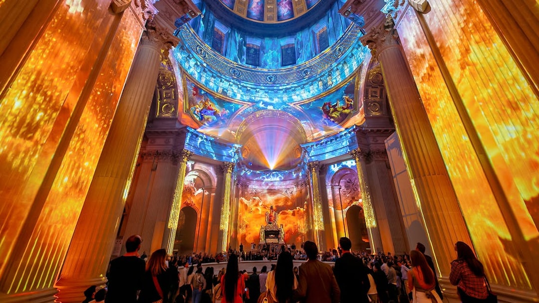 Immersive light show at Invalides, Paris, with vibrant projections on columns and dome.