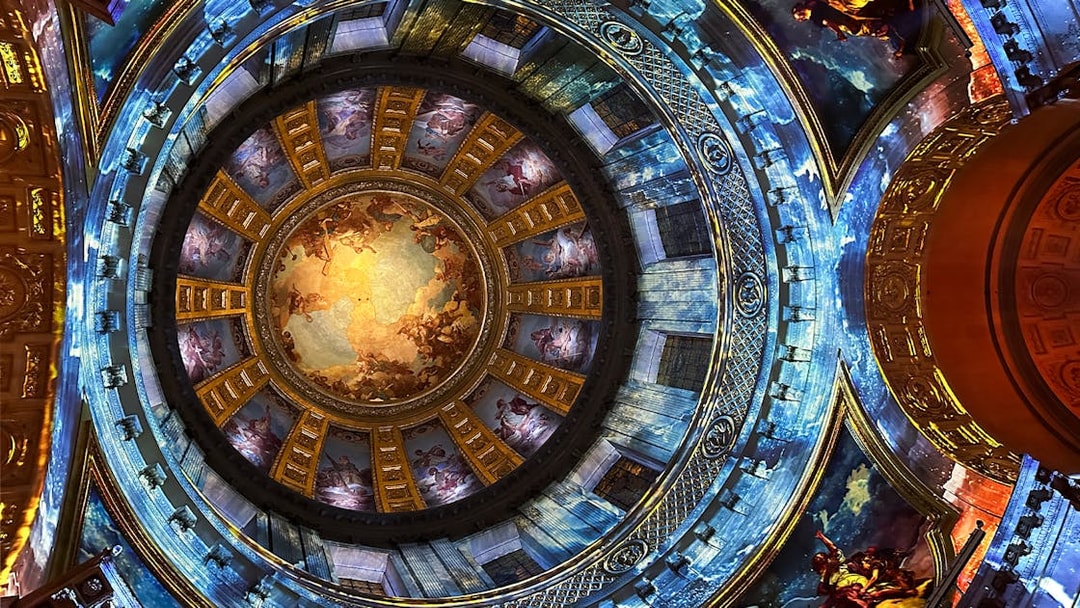 Dome interior with vibrant frescoes at Invalides Aura Immersive Experience, Paris.