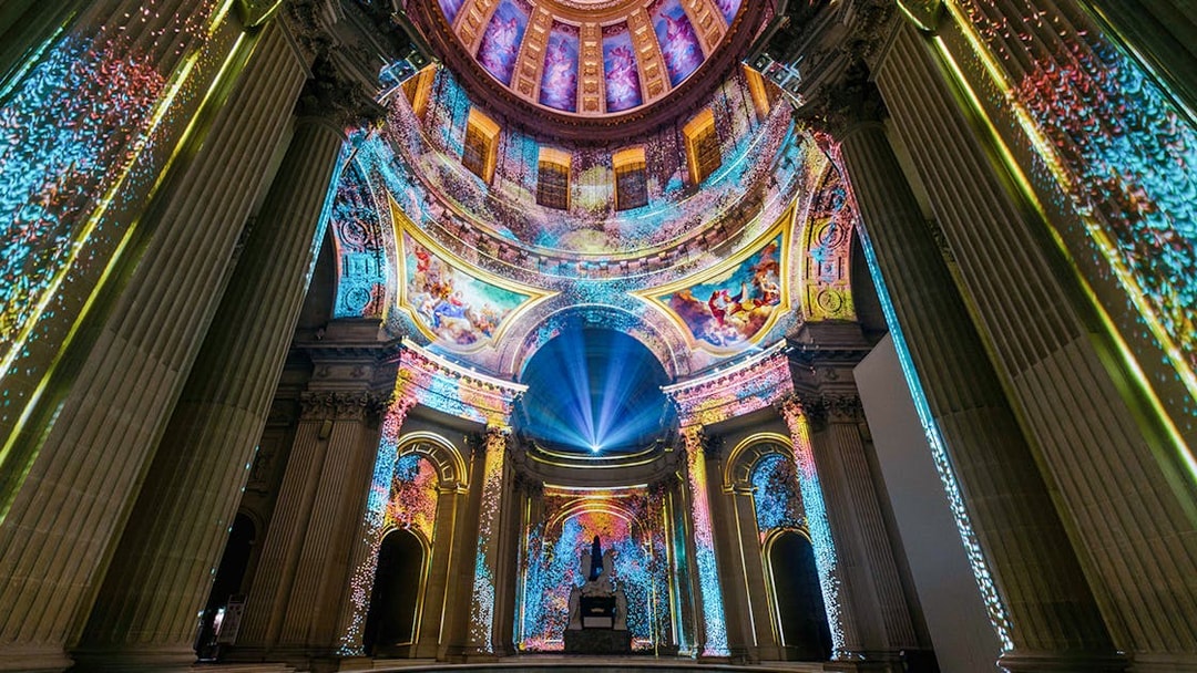 Immersive light display inside Invalides dome, Paris, showcasing vibrant projections.