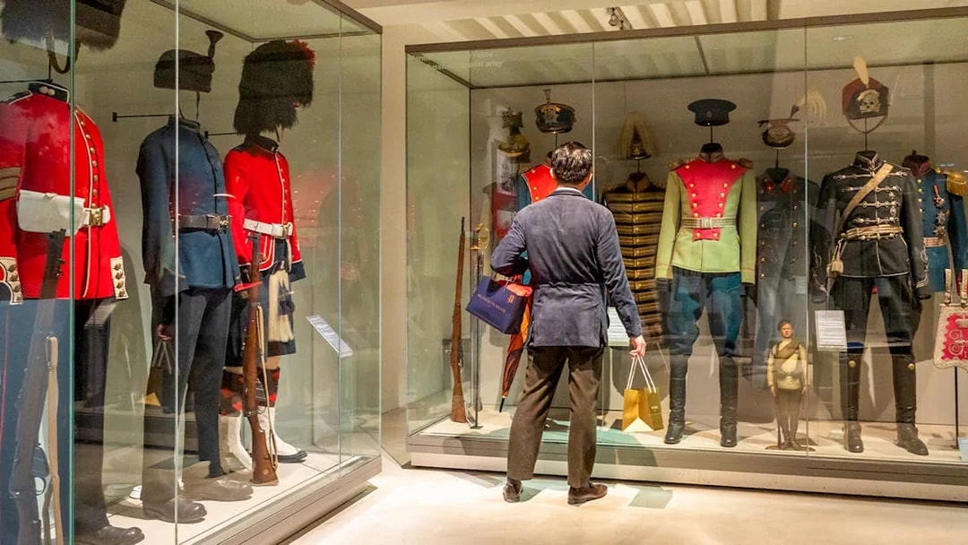 Army uniforms on display at The Army Museum with visitor observing.