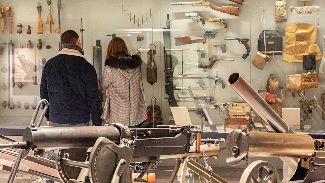 Visitors viewing historical weapons at Paris Army Museum exhibition.