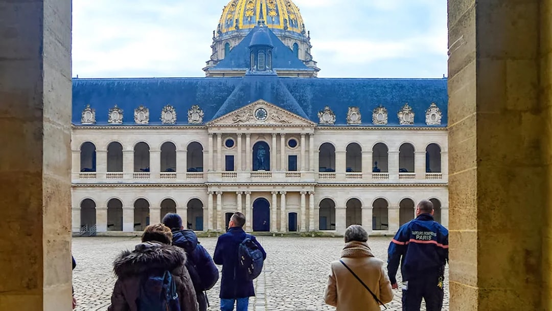 Visitors walking in the courtyard of Les Invalides, Paris, with the dome in view.