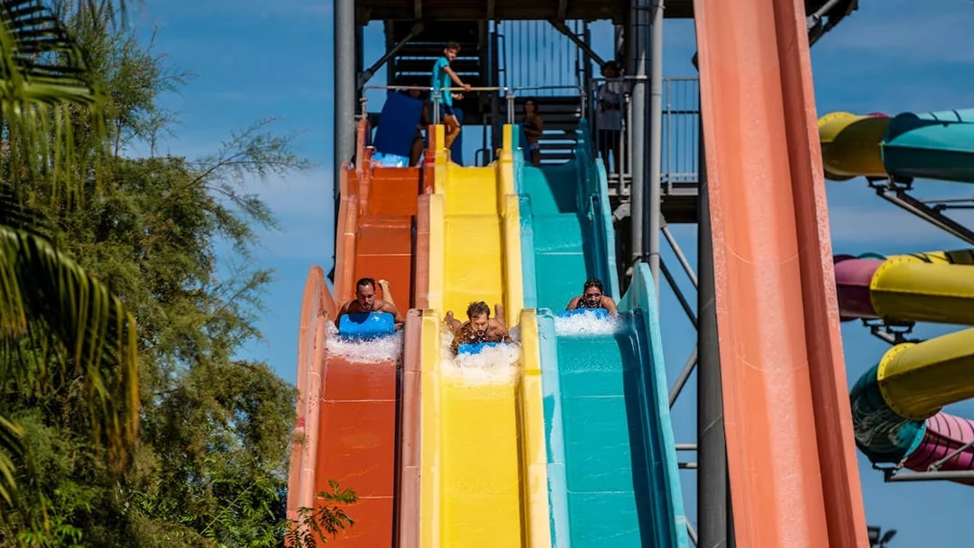 Visitors enjoying colorful water slides at Isla Mágica theme park.