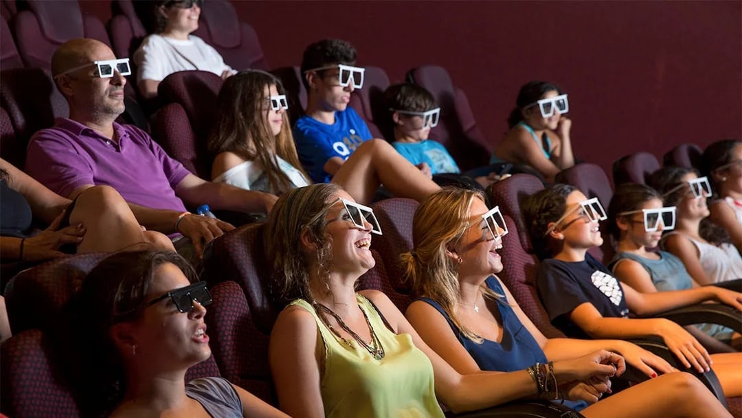 Visitors enjoying a 4D cinema experience at Isla Magica, wearing 3D glasses.