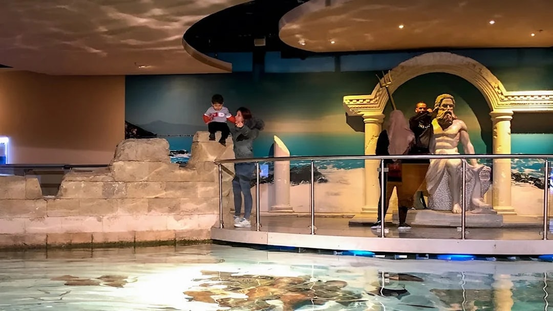 Visitors exploring the Istanbul Aquarium near a Poseidon statue.