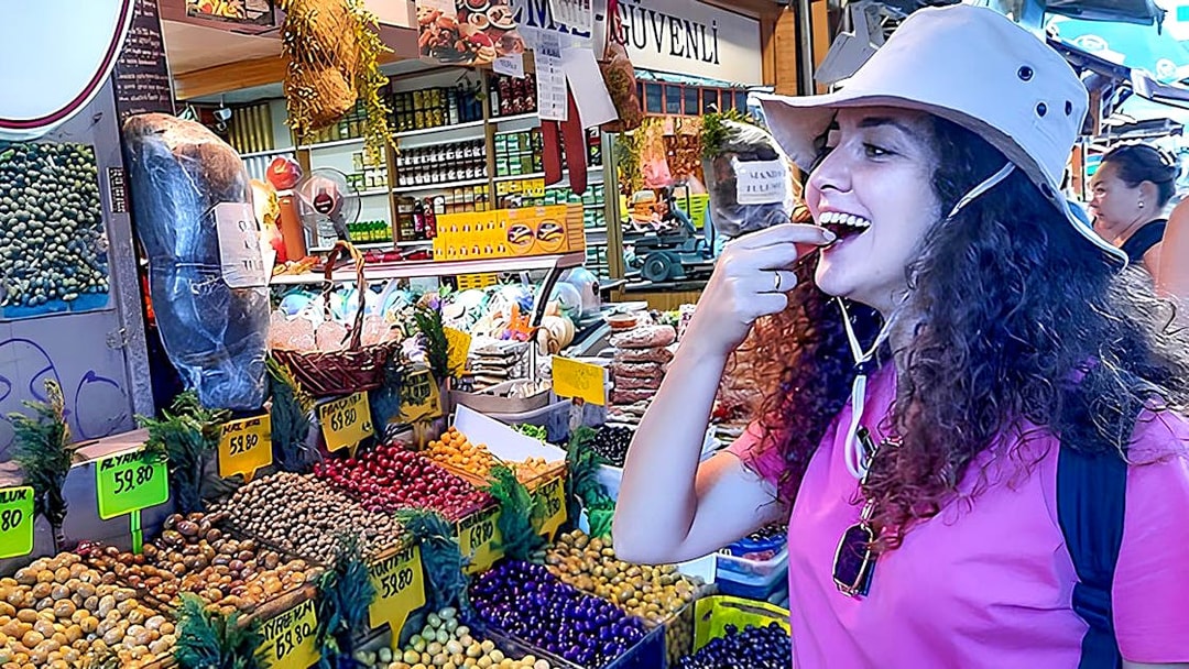 Traveler tasting olives at a vibrant market on Istanbul's Asian side during a walking tour.