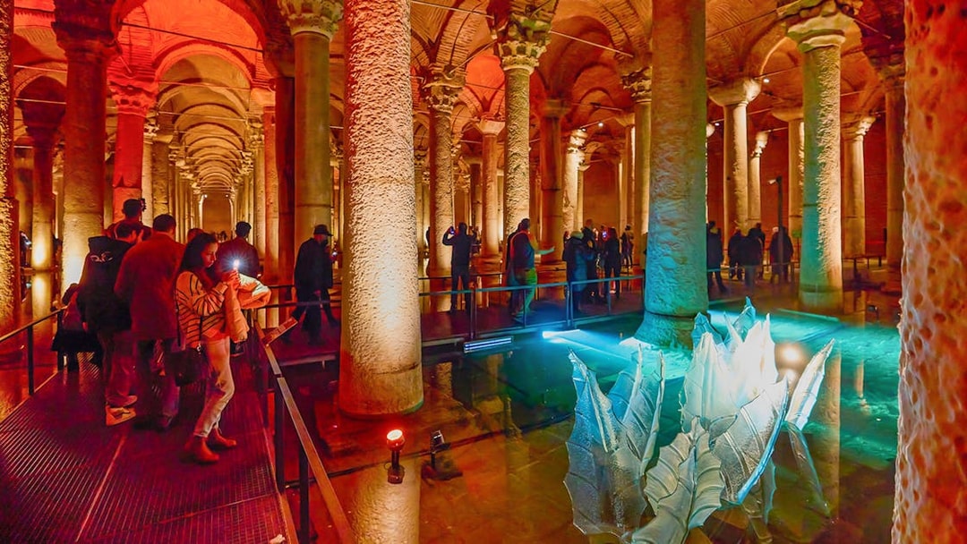 Visitors exploring the illuminated Basilica Cistern in Istanbul.