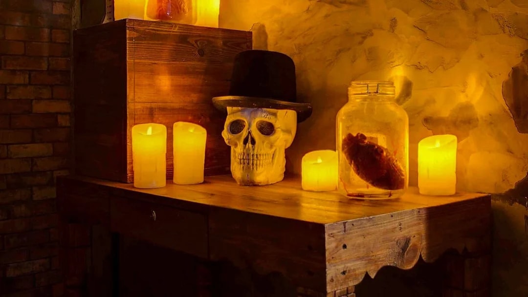 Skull with hat and candles on a wooden table in Jack The Ripper Escape Room, Dubai.