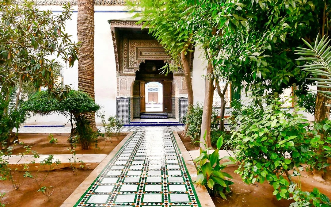 Bahia Palace gardens with tiled pathway and lush greenery in Marrakech, Morocco.