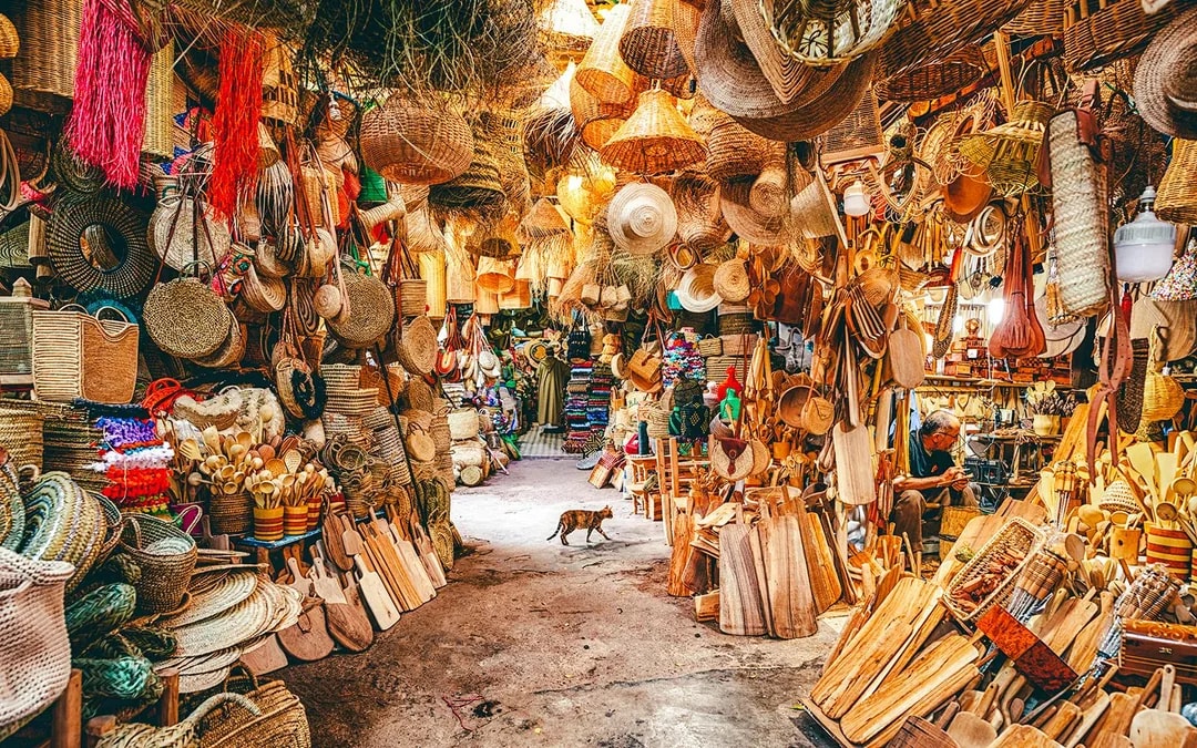 Bustling market stall with woven baskets and wooden crafts in Marrakech souk, Morocco.