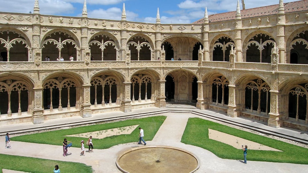 Jeronimos Monastery courtyard garden with ornate arches and central fountain, Lisbon.