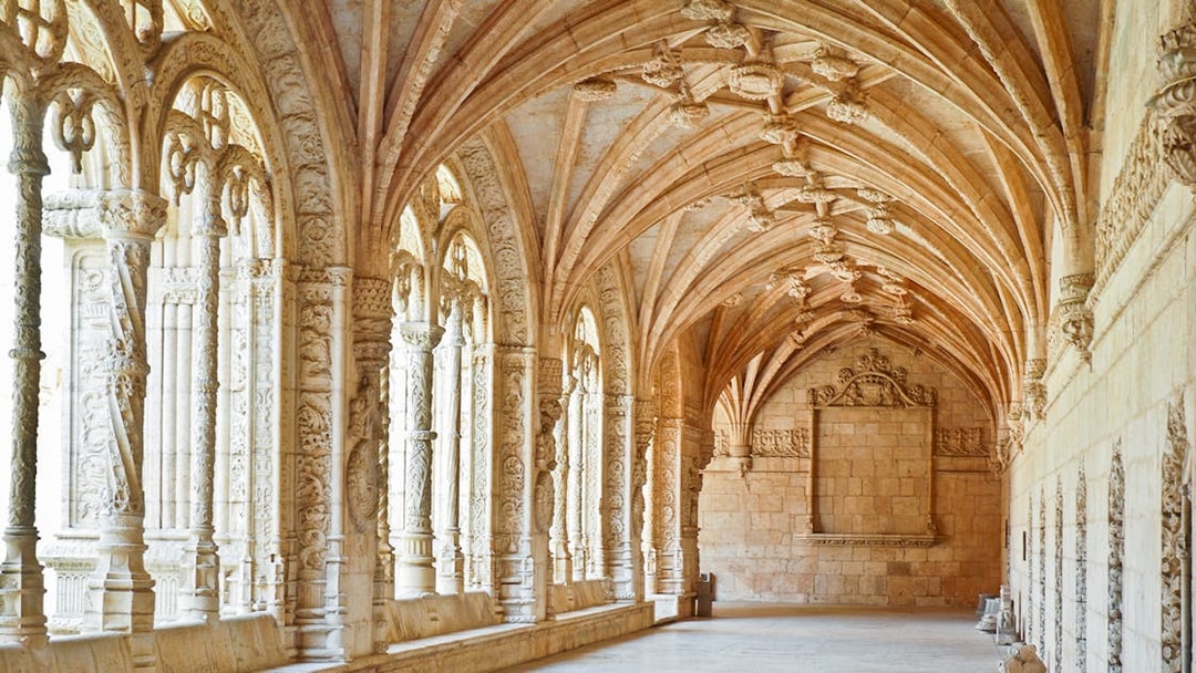 Jernimos Monastery interior with ornate arches and detailed stone carvings in Lisbon, Portugal.