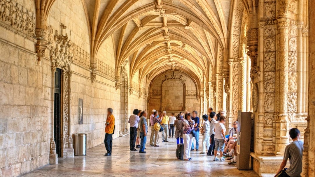 Visitors exploring the ornate cloisters of Jeronimos Monastery in Lisbon, Portugal.
