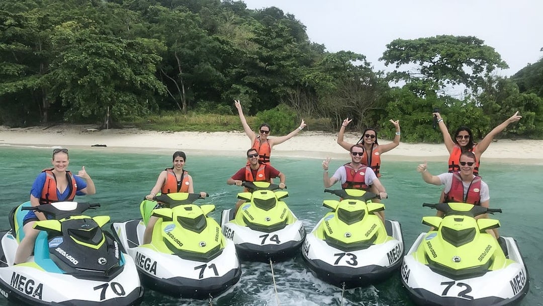 Group enjoying jet ski ride near Langkawi beach with lush greenery in the background.